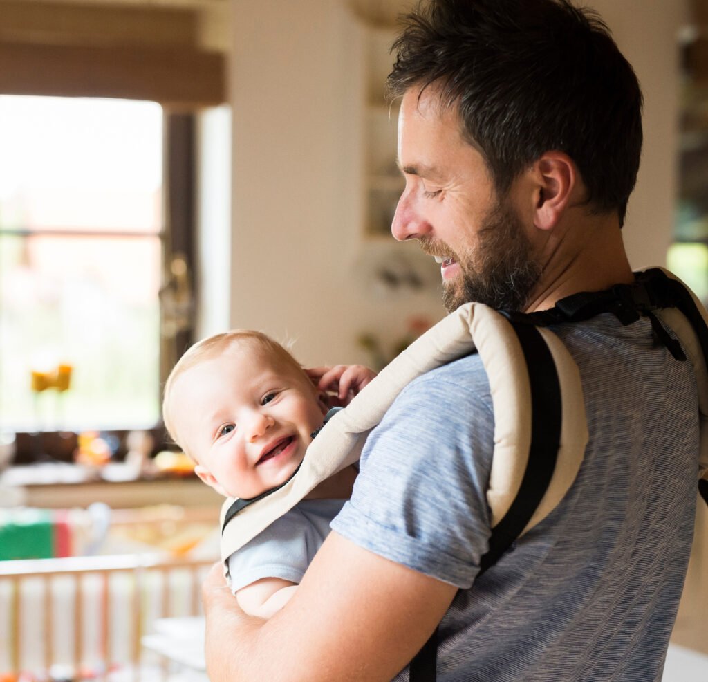 Happy father with baby in baby carrier at home 2022 12 16 22 36 27 utc